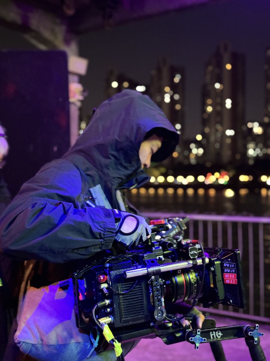 Cinematographer with camera setup handheld, night time, purple lights